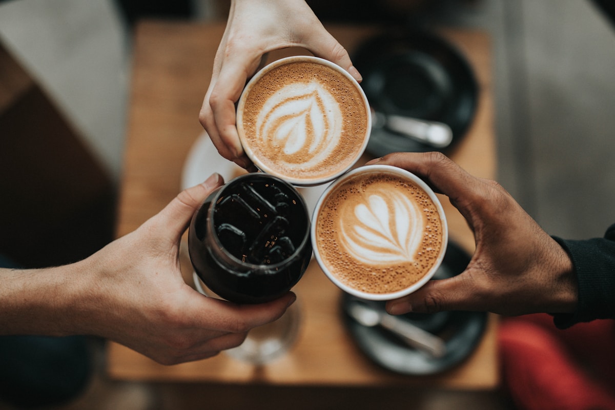 Three people sharing coffee around a cafe table